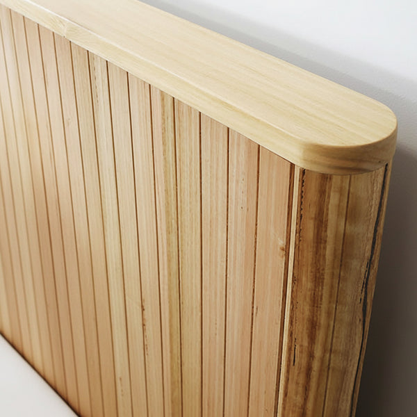 Wood slat headboard with dark green bedding and two white pillows