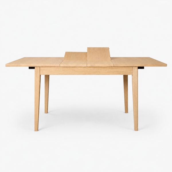 A light natural wood extendable dining table with four tapered legs, shown from a front three-quarter angle on a seamless white background.