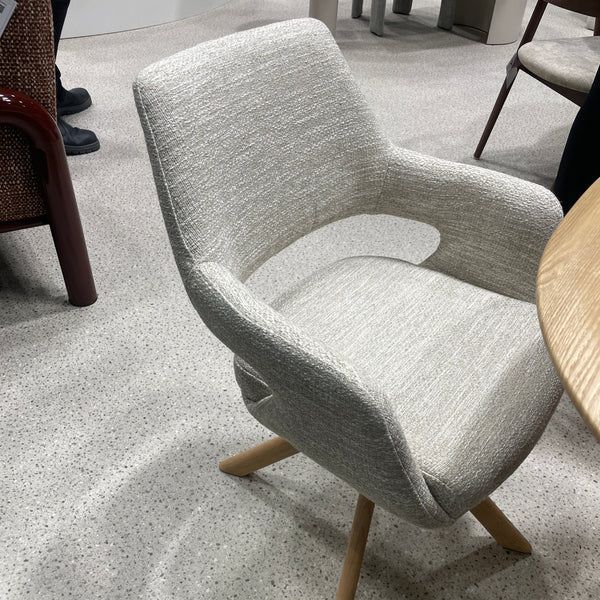 Light gray upholstered dining chair with curved backrest and tripod legs