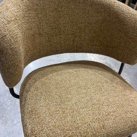 A close-up of a modern upholstered chair with a curved back and seat, covered in a textured beige and brown woven fabric, with black metal legs visible.