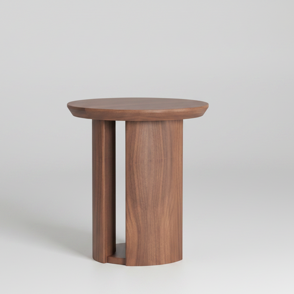 A modern round wooden side table with a natural walnut finish, featuring a thick circular top and two integrated cylindrical legs with a small open shelf at the base, shown on a solid white background.