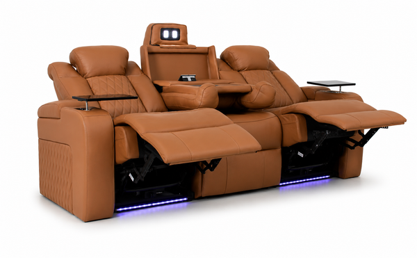 A luxury home theater recliner sofa in tan leather, shown with all three seats reclined and extended. Features include a central console with a screen, side tables, and blue LED under-seat lighting on a white background.