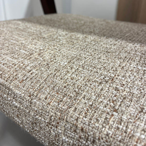 Close-up of a textured woven upholstery fabric in a warm beige and off-white tone, showing the detailed weave pattern.