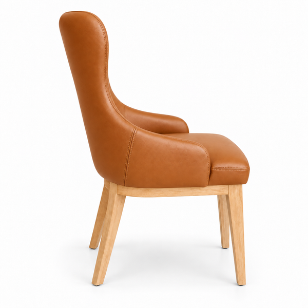 A modern wingback dining chair with a warm cognac brown faux leather upholstered seat and backrest, supported by light natural wood legs, shown from a three-quarters angle on a white background.