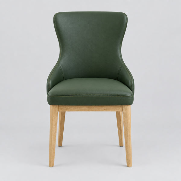 A modern dining chair with a dark green upholstered seat and backrest, supported by light natural wood legs, shown in a furniture showroom.